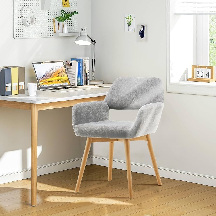 A clean desk setup with a notebook, pen, and accent chair in the background.