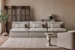 A comfortable modern couch sits in a bright, sunlit living room with minimalist decor.