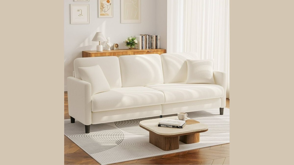 A modern three-seater sofa positioned in a bright, spacious living room interior.