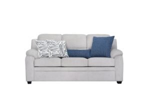 A modern three-seater sofa sits in a bright living room as a central furniture piece.
