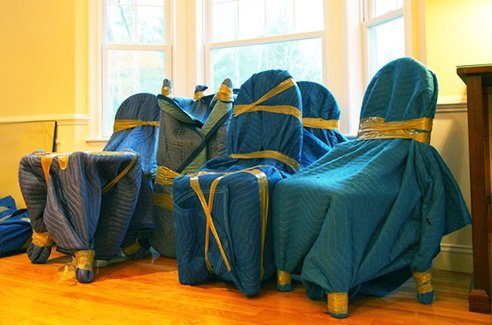 A wooden dining chair being carefully prepared for moving in a home.