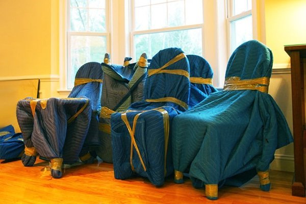 A professional mover wraps dining room chairs securely for a safe home relocation.