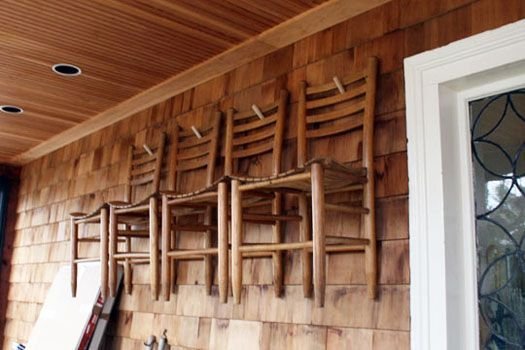 A group of dining room chairs safely covered and stored in a bright room.