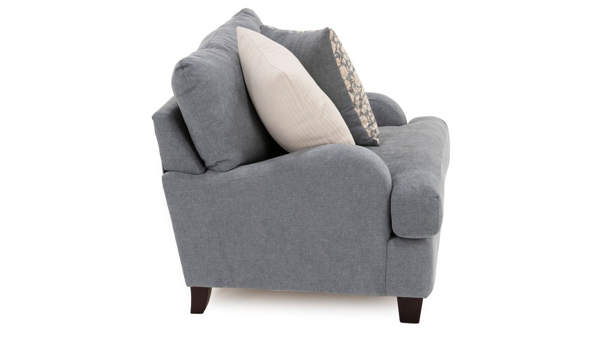 A neutral beige armchair sits in a sunlit living room to demonstrate how wide is an armchair.