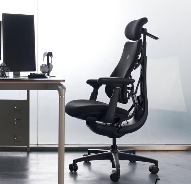 A clean office workspace featuring an ergonomic chair and a digital FAQ display.