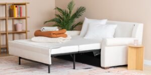 A modern sleeper chair unfolds into a bed in a bright, compact studio apartment.