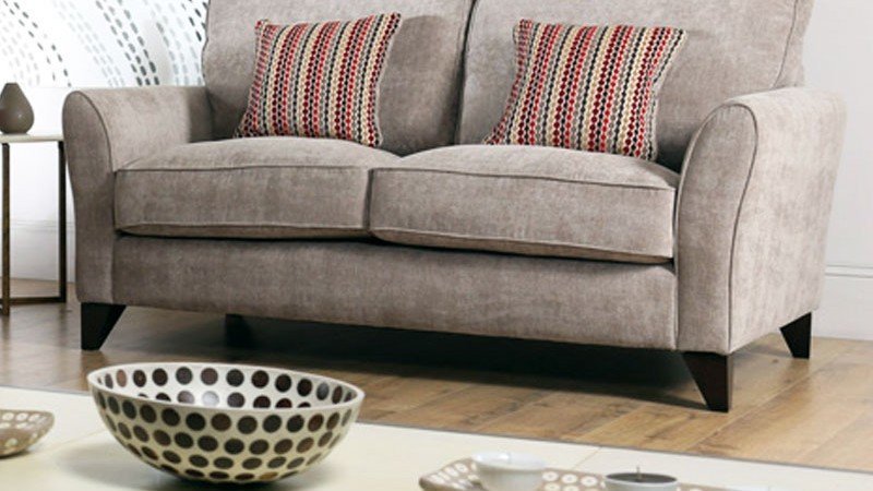 A hand using a screwdriver to adjust the leveling feet of a sofa suite.