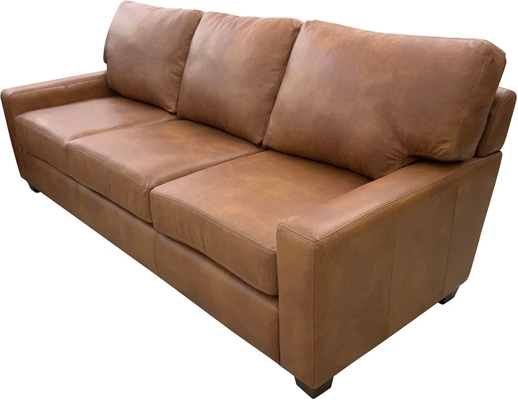 A person measures floor space near a large three-seat couch for correct placement.