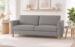 A modern three-seat couch sits comfortably in a well-lit, contemporary living room setting.