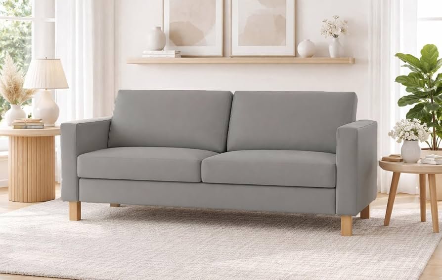 A modern three-seater sofa centered in a bright and airy living room.