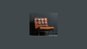 A modern side chair without arms placed under a table in a bright room.