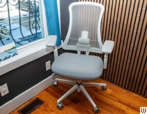 A modern ergonomic desk chair centered in a clean, bright home office workspace.