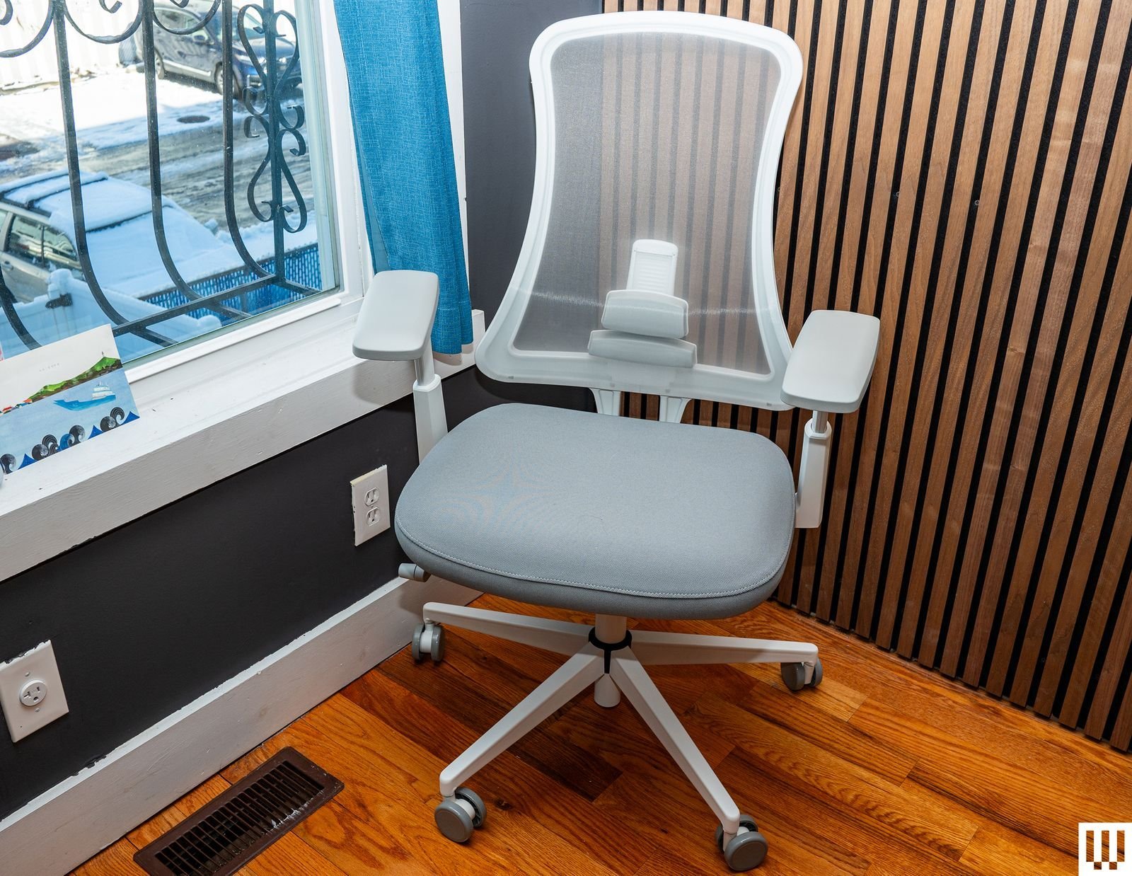 A modern ergonomic desk chair centered in a clean, bright home office workspace.