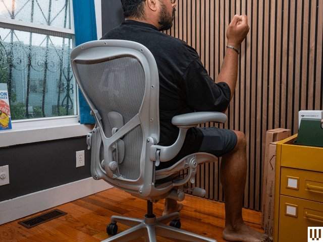 A modern ergonomic computer chair positioned in a bright, minimalist home office space.