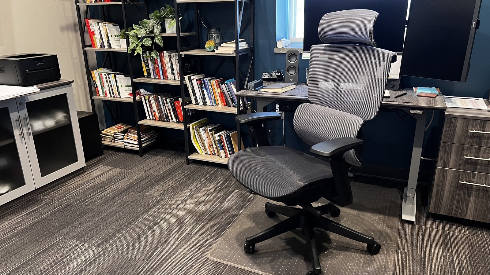 A clean and organized office workspace with an ergonomic chair ready for work.