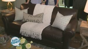 A brightened brown couch in a sunlit living room with cream textiles.