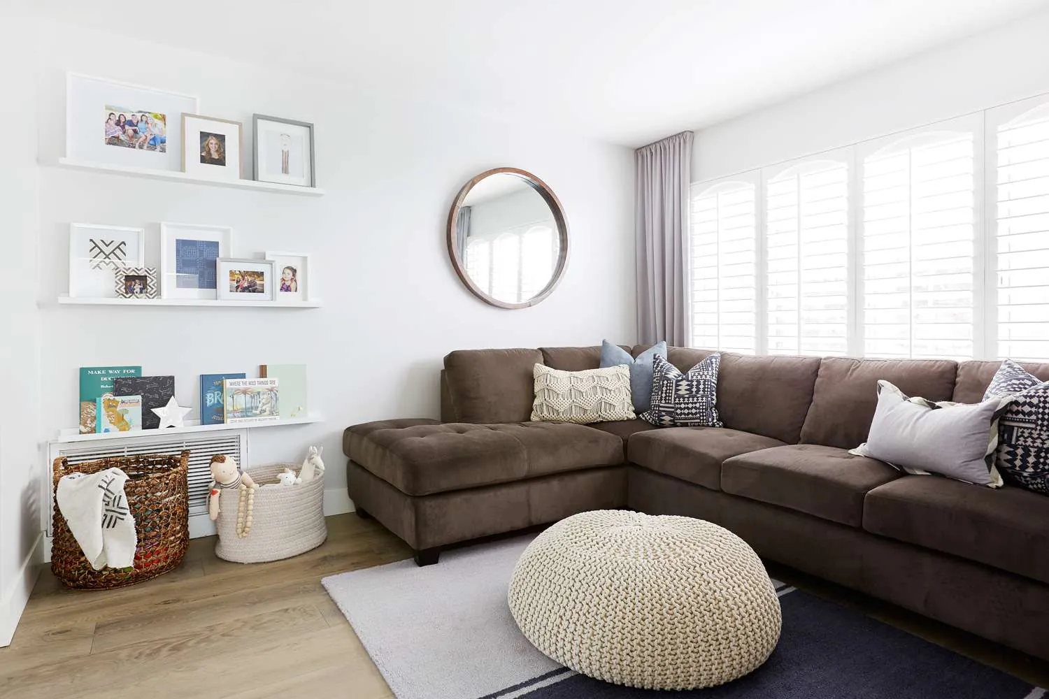 A collection of pillows, blankets, and rug samples laid out for styling a sofa.