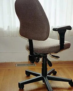 A damaged rolling chair wheel showing wear from use on a concrete floor.