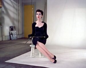 An elegant woman demonstrates how to sit like a model in a studio.