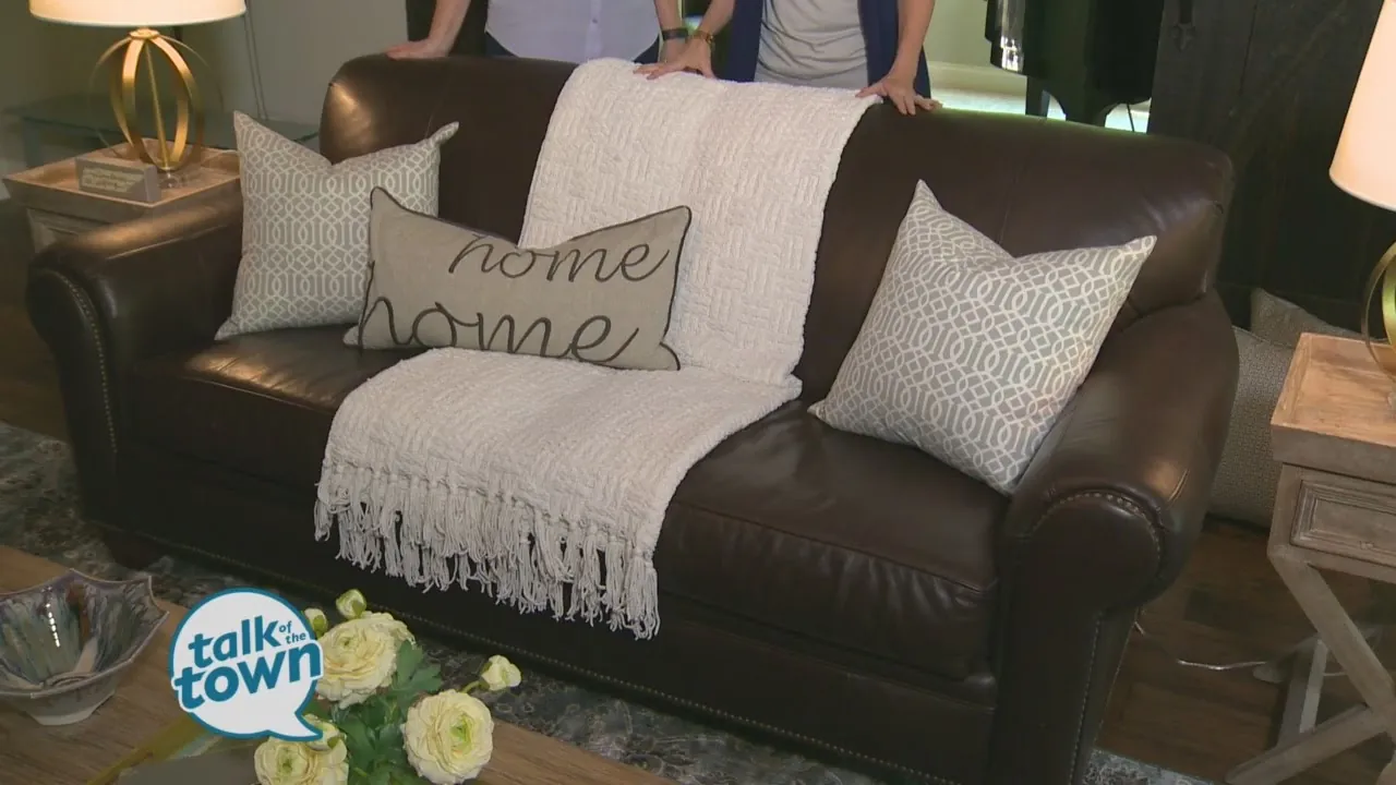 Four large light-colored pillows arranged on a brown sofa to balance the space.