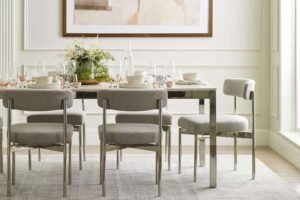 Four wooden dining chairs arranged around an oak table in a bright room.