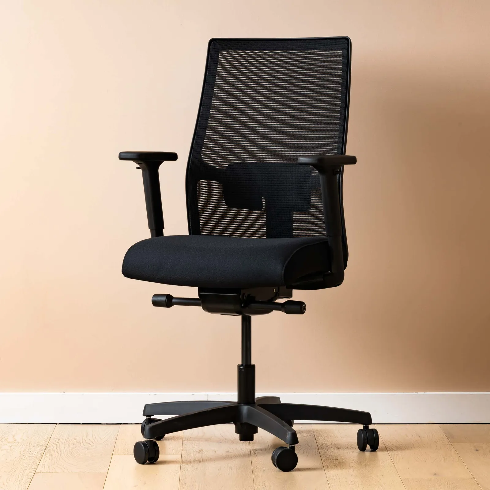 A grey office chair tipped over with a cracked plastic armrest.