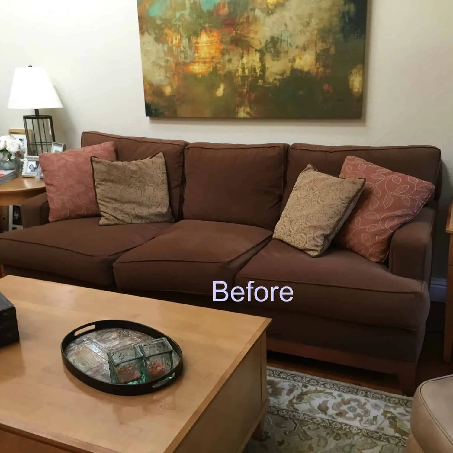 Hands placing a patterned pillow on a brown sofa during the styling process.