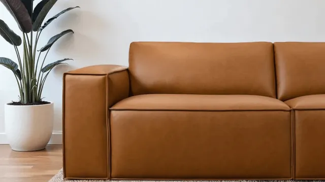 Hands vacuuming the crevices of a sectional couch to maintain fabric quality.