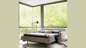 A modern comfortable chair bed sits in a bright and cozy living room.