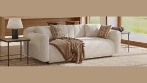 A modern fabric couch in an empty living room with a measuring tape.