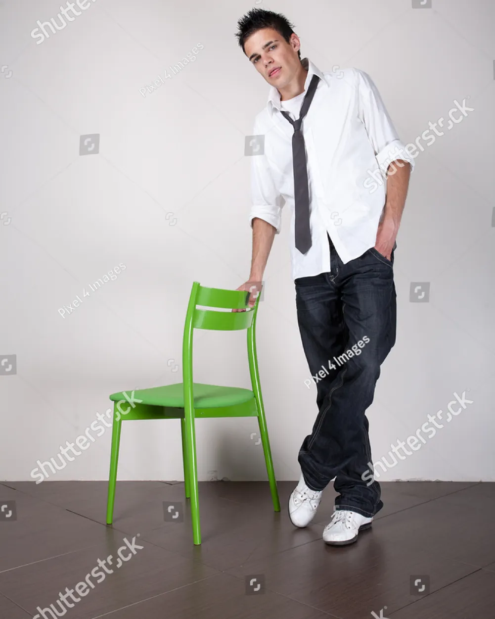 A person adjusting their posture while seated on a high chair in a studio.