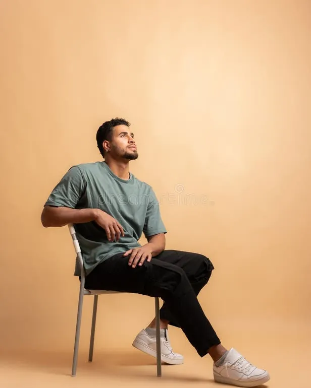 A person demonstrating a relaxed and sophisticated seated posing style on a low chair.