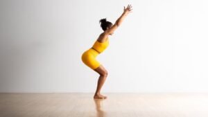 A person practicing elegant seated poses for a professional photoshoot in a studio.