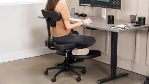 A person sitting cross-legged on a wide office chair at a desk.