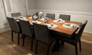 A solid oak dining room table stands in a bright, modern dining space.